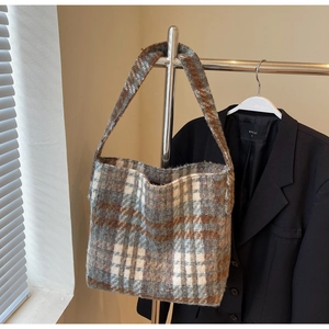 Detailopname van de vintage tweed textuur en het blauw-bruine ruitpatroon op de tas