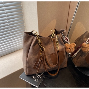 Detail view of brown vintage leather tote with gold chain strap and plush bear charm
