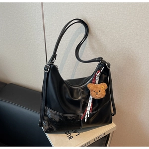 Détail du sac hobo noir avec surpiqûres blanches et pendentif ours en peluche