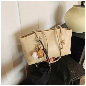 Detail of beige faux leather tote bag featuring a decorative baseball and glove charm