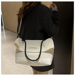 Detailed close-up of white corduroy tote bag with black woven rope handles and texture