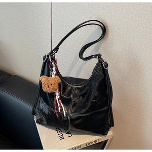 Détail du sac cabas en simili cuir noir avec surpiqûres blanches et pendentif ours