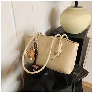 Detail of beige tote bag with litchi texture PU leather and baseball glove pendant charm