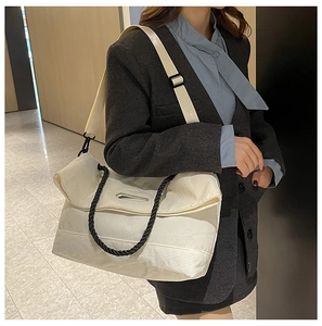 Detail view of cream corduroy tote bag featuring black woven handles and a soft ribbed texture
