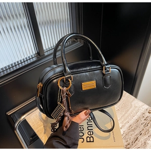 Detailaufnahme der schwarzen Boston Bag aus Leder mit goldenem Logo und Anhängern