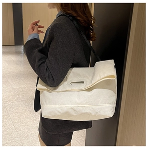 Detail of off-white corduroy tote bag with black woven rope strap on a model