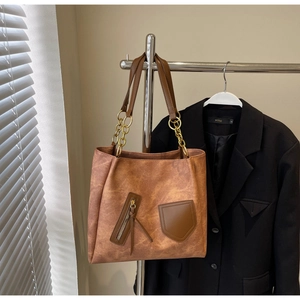 Detail of vintage brown tote bag showing leather texture and gold chain strap attachment