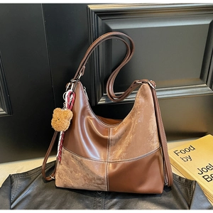 Détail d'un sac hobo patchwork marron avec coutures contrastées et porte-clé ours