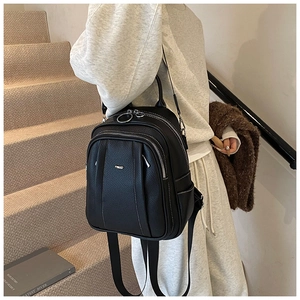 Detailansicht eines schwarzen Kunstleder-Rucksacks mit silbernen Reißverschlüssen am Modell