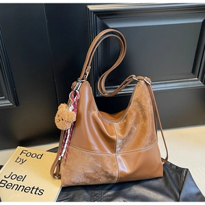Détail du sac hobo marron rétro avec coutures blanches et breloque ours