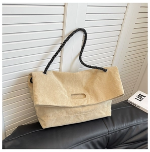 Detail of corduroy tote bag featuring a round cutout handle and black rope strap