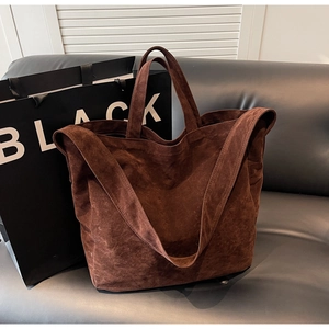 Brown suede tote bag with large capacity for daily use, shown on a black sofa