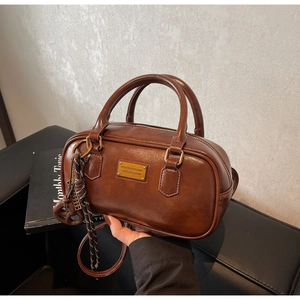 Nahaufnahme der braunen Boston Bag mit mattem PU-Leder und goldener Logo-Plakette