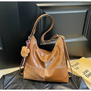 Détail du sac hobo rétro marron avec surpiqûres contrastées et breloque ours