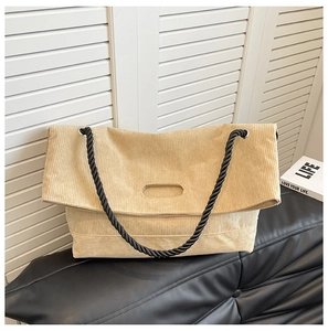 Detail of beige corduroy tote bag showing woven handles and rectangular cutout grip