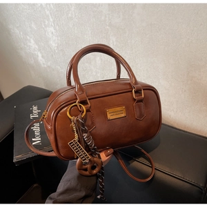 Details der braunen Vintage Boston Tasche mit goldenem Abakus-Anhänger und Metallplatte