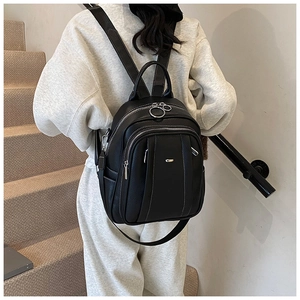 Detail eines schwarzen Lederrucksacks mit weißen Nähten und silbernen Reißverschlüssen