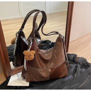 Détail du grand cabas vintage marron avec coutures contrastées et breloque ours en peluche