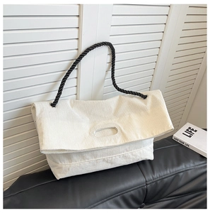 Detail of off-white corduroy tote bag showing textured fabric and black rope shoulder strap