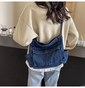 Detail of blue denim crossbody bag with multiple pockets and vintage workwear style