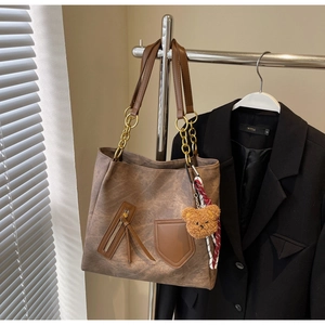 Detail of distressed brown tote bag with decorative zipper and plush bear charm