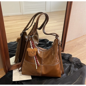 Détail du sac hobo marron avec coutures contrastées en daim et breloque ours en peluche