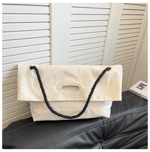 Macro view of cream corduroy texture and black rope strap on large tote bag