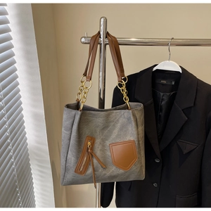 Detail view of large tote bag with contrast stitching and golden chain handle hardware