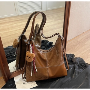 Détails du sac cabas marron vintage avec coutures blanches et breloque ours doux