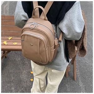 Nahaufnahme eines braunen Lederrucksacks mit Metallreißverschlüssen in herbstlicher Parkszene