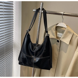 Gros plan sur un sac hobo noir avec des surpiqûres blanches et deux fines bandoulières