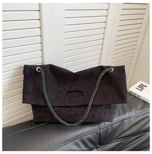 Detail of black corduroy tote bag showing ribbed texture and twisted rope shoulder strap