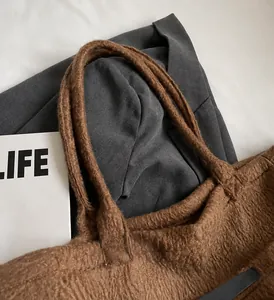 Detail view showing the soft brown plush material and durable handle of the tote bag
