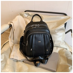 Detail eines schwarzen Lederrucksacks mit Kieselstruktur und mehreren Reißverschlussfächern