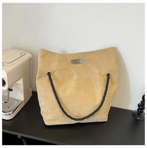 Detail of light beige corduroy tote bag with black rope handle and oval cutout grip