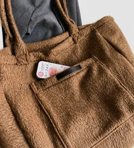 Detail of a brown plush tote bag showing a functional exterior pocket and soft texture