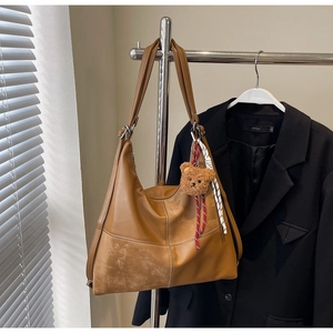 Détail d'un sac cabas marron avec surpiqûres contrastées et un charmant porte-clés