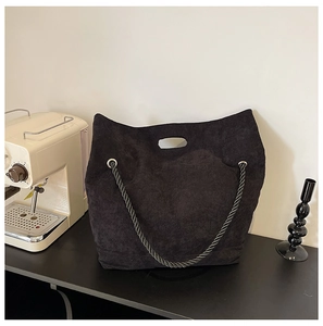 Close-up of black corduroy tote bag with rope handles and ergonomic cutout design