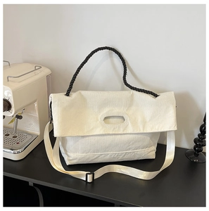 Close-up of cream corduroy tote bag texture with black rope handle on a cafe table