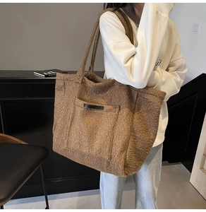 Brown fuzzy tote bag with front pocket and double handles shown on a model
