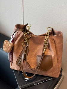 Brown textured tote bag with golden chain straps and cute plush bear charm on magazines