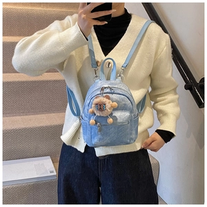 Detail van een lichtblauwe mini-rugzak met denim textuur en een schattige teddybeer