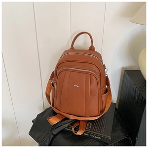 Detailaufnahme des braunen Kunstleder-Rucksacks mit Silberlogo auf schwarzem Ledergrund