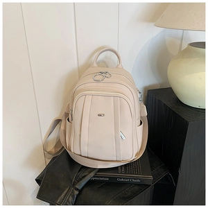 Detailansicht des cremefarbenen Lederrucksacks auf einem Tisch mit Lampe und Buch