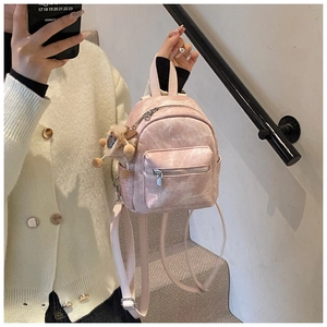 Detail van roze mini rugzak met geplooide textuur en pluchen cartoon hanger voor meisjes