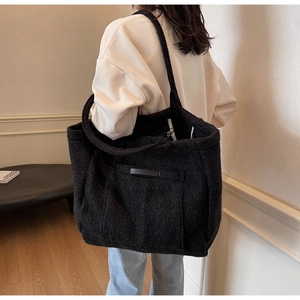 Detail of black fuzzy faux shearling tote bag showing plush texture and wide strap