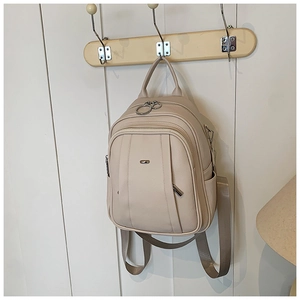 Detailansicht des cremefarbenen Rucksacks aus Leder mit Silberlogo und Fronttasche