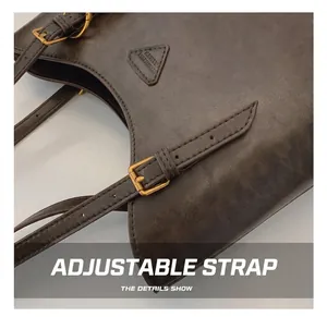 Détail de la bandoulière réglable avec boucle dorée sur un sac cabas en cuir marron