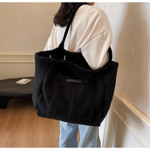Close-up of a black plush tote bag showing fuzzy wool texture and front pocket detail