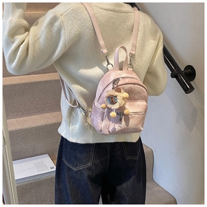Gedetailleerd beeld van een roze rugzak met een schattige pluche schaap hanger op model